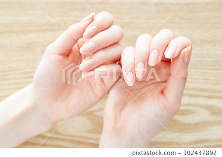 A woman's hand checking the condition of her nails A woman's hand checking the condition of her nails 102437892