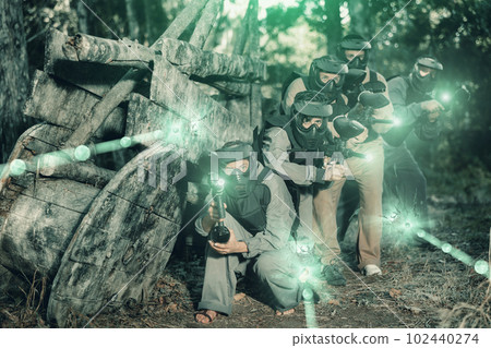 Paintball players of one team in camouflages and masks aiming with gun in shootout Paintball players of one team in camouflages and masks aiming with gun in shootout 102440274