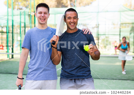 Portrait of happy man and teenage boy padel tennis players Portrait of happy man and teenage boy padel tennis players 102440284