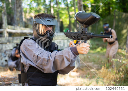 Paintball player recklessly aims with a gun on battlefield 102440331