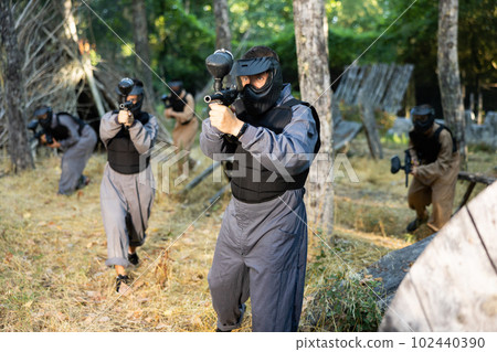 Impudent teams facing on battlefield in outdoor paintball arena during match 102440390