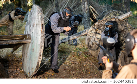Group of men and women shooting with paintball markers 102440391