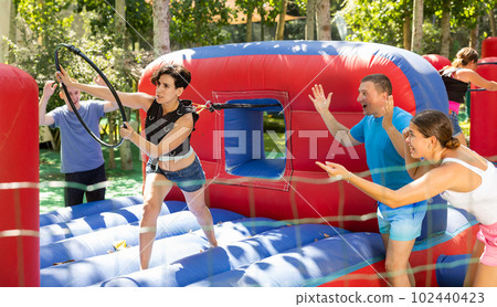 Cheerful woman having funny competition in collect of hoops on inflatable trampoline Cheerful woman having funny competition in collect of hoops on inflatable trampoline 102440423