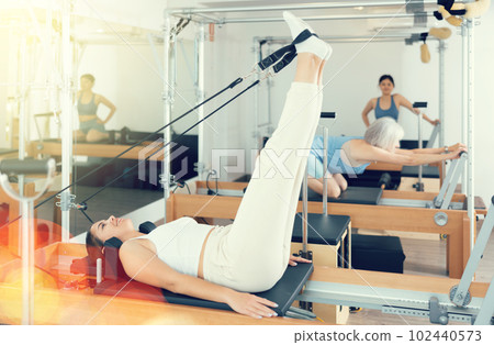 Concentrated young girl practicing exercises on Pilates reformer 102440573
