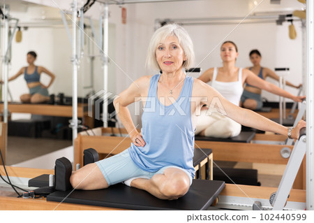 Senior woman doing stretching exercises on pilates reformer Senior woman doing stretching exercises on pilates reformer 102440599