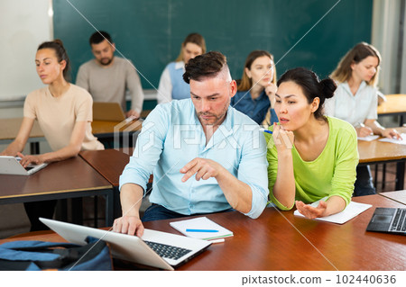 Man and woman students uisng laptop and discussing lesson 102440636