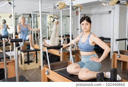 Young positive woman doing Pilates on special equipment in gym 102440668