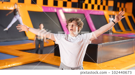 Teenage boy in sport clothes doing exercises in trampoline arena 102440673