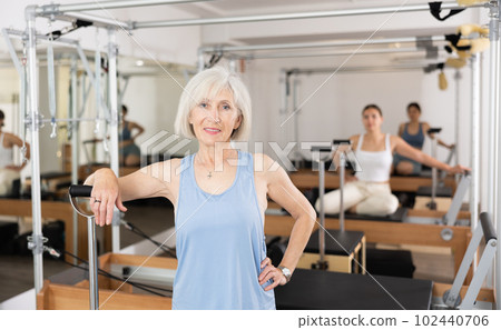 Smiling elderly woman leaning on wunda chair in pilates studio Smiling elderly woman leaning on wunda chair in pilates studio 102440706