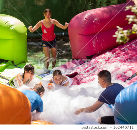 Joyful adults in inflatable pool with foam competing to collect balls Joyful adults in inflatable pool with foam competing to collect balls 102440711