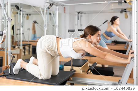 Young girl doing exercises on reformer in pilates studio Young girl doing exercises on reformer in pilates studio 102440859