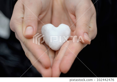 Snow in the shape of a heart in a woman's hands. Snow in the shape of a heart in a woman's hands. 102442476