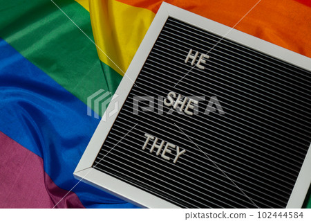 HE SHE THEY text Neo pronouns concept on Rainbow flag background gender pronouns. Non-binary people rights transgenders. Lgbtq community support assume my gender tolerance equal rights 102444584