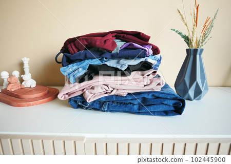 Stack of clothes on table indoor. 102445900