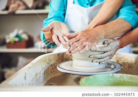 They have a hands-on marriage. a senior couple making a ceramic pot together in a workshop. 102445973
