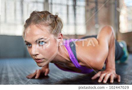 Pain is temporary but quitting lasts forever. a sporty young woman doing push-ups at the gym. 102447029