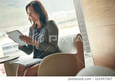 Never tied down to a desk thanks to wireless technology. a young businesswoman using adigital tablet at work. 102447067