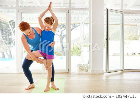 Teaching posture and balance. a mother and daughter doing yoga together in the living room. 102447115