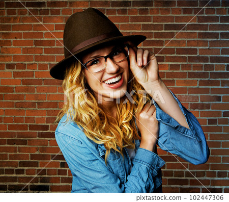 I see this life and Im loving it. a beautiful and trendy young woman posing against a brick wall. 102447306