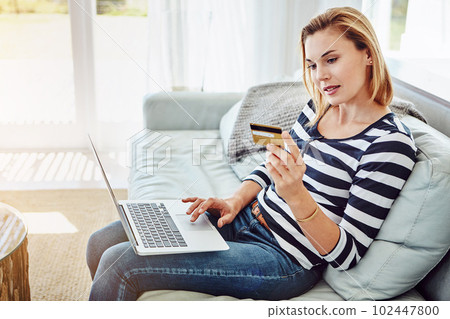 Shopping online. High angle shot of an attractive young woman shopping online from the comfort of home. Shopping online. High angle shot of an attractive young woman shopping online from the comfort of home. 102447800