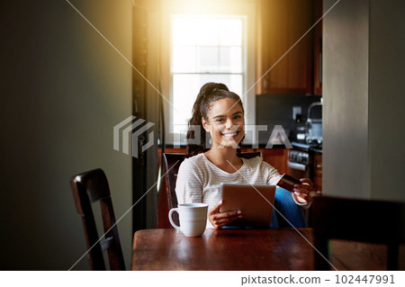 Online shopping is just a click away. a young woman drinking coffee and shopping online with her digital tablet at home. 102447991