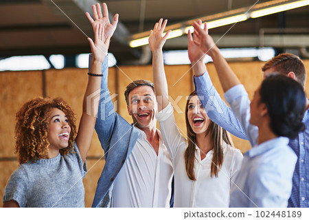 Celebrating another team success. a group of smiling colleagues high fiving together in an office. Celebrating another team success. a group of smiling colleagues high fiving together in an office. 102448189