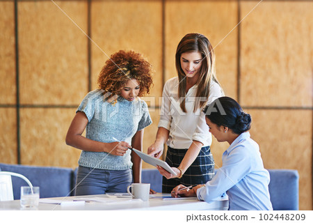 Theyre leaders in this office. a group of colleagues working together on a digital tablet in an office. 102448209