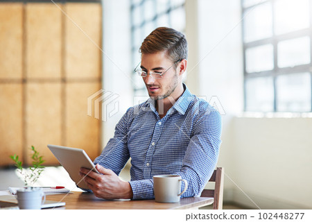 Managing his business network with modern technology. a young businessman using a digital tablet in an office. Managing his business network with modern technology. a young businessman using a digital tablet in an office. 102448277