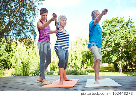 Stay fit in your senior years. a yoga instructor guiding a senior couple in a yoga class. Stay fit in your senior years. a yoga instructor guiding a senior couple in a yoga class. 102448278