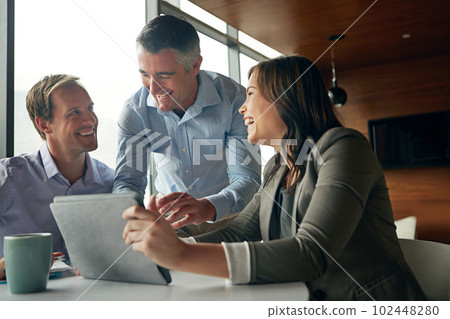 Coming up with great ideas together. a group of businesspeople talking together over a digital tablet in an office. Coming up with great ideas together. a group of businesspeople talking together over a digital tablet in an office. 102448280