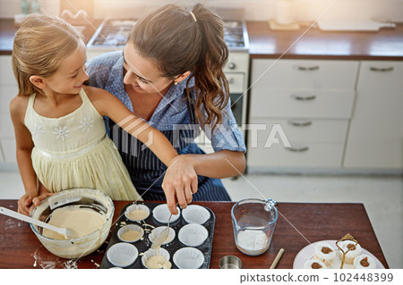They make the best cupcakes ever. a mother and her daughter baking in the kitchen. 102448399