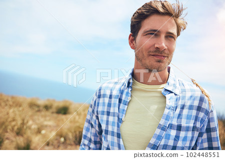 Hes getting back to nature. a young man in a field on a sunny day. Hes getting back to nature. a young man in a field on a sunny day. 102448551