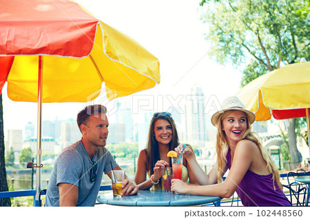 Having drinks with a few close friends. three young friends sitting at an outdoor cafe. Having drinks with a few close friends. three young friends sitting at an outdoor cafe. 102448560