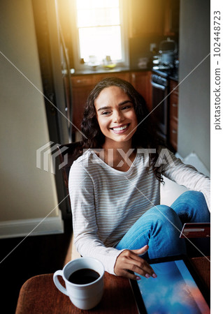 Shopping from the comfort of home. a young woman drinking coffee and shopping online with her digital tablet at home. 102448723