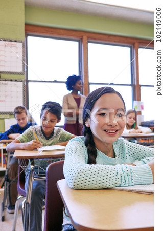 I love being at school. a young girl sitting in class with her teacher and classmates blurred in the background. I love being at school. a young girl sitting in class with her teacher and classmates blurred in the background. 102449006