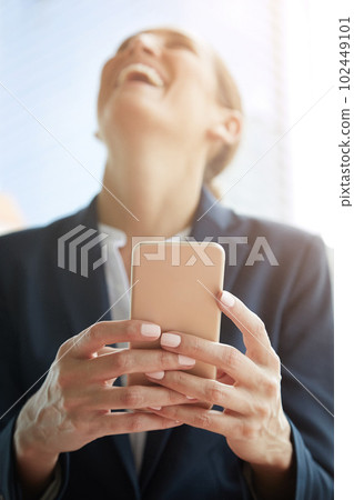 The deal went through. a young businesswoman laughing while using a cellphone. 102449101