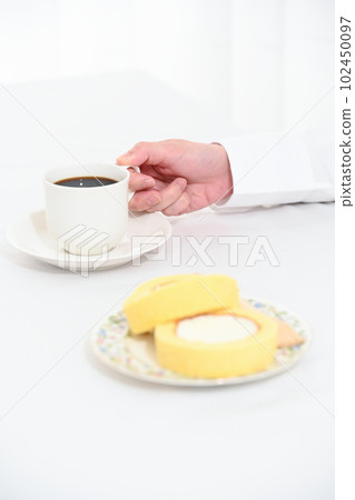 A hand holding a coffee cup and a roll cake 102450097