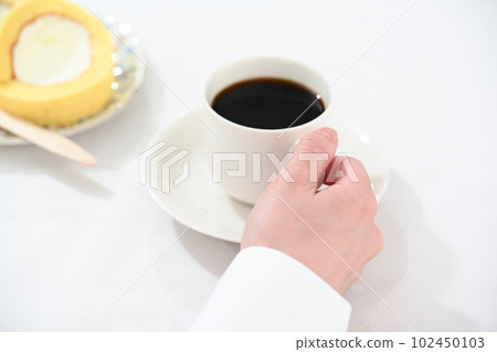 A hand holding a coffee cup and a roll cake A hand holding a coffee cup and a roll cake 102450103