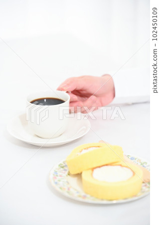 一隻手拿著咖啡杯和蛋糕卷 102450109