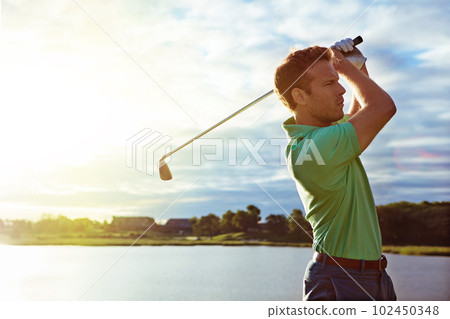 Living life swing by swing. a man practicing his swing on the golf course. 102450348