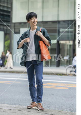 A man in his 20s standing on a street corner 102450373