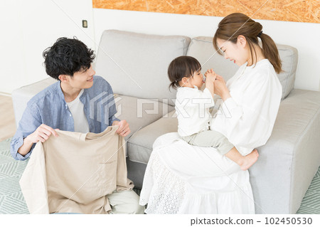 丈夫幫忙疊衣服做家務,妻子在客廳照顧孩子 丈夫幫忙疊衣服做家務,妻子在客廳照顧孩子 102450530