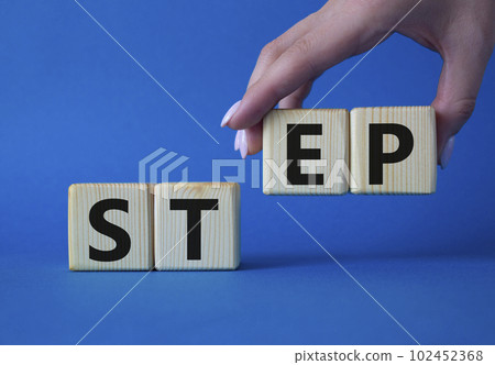 Step symbol. Concept word Step on wooden cubes. Businessman hand. Beautiful blue background. Business and Step concept. Copy space. 102452368