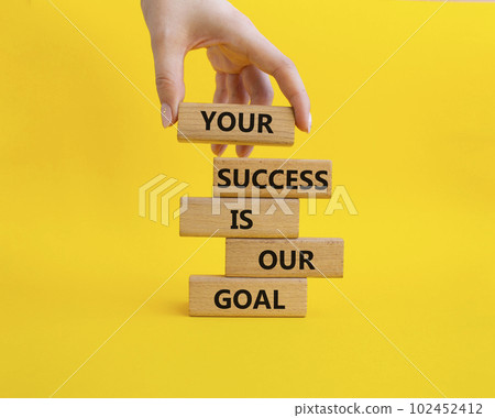 Your success is our goal symbol. Wooden blocks with words Your success is our goal. Beautiful yellow background. Businessman hand. Business and Your success is our goal concept. Copy space 102452412