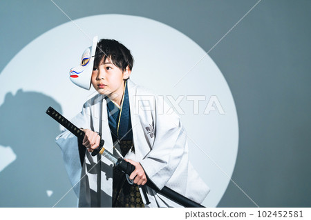 A boy wearing a kimono and holding a sword A boy wearing a kimono and holding a sword 102452581
