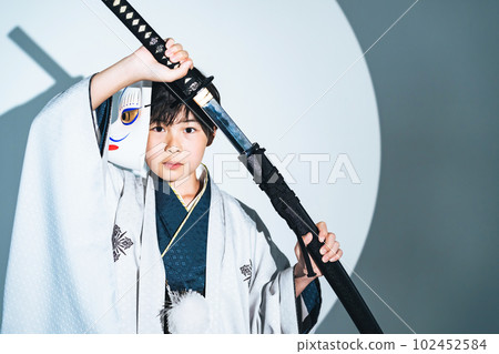A boy wearing a kimono and holding a sword A boy wearing a kimono and holding a sword 102452584