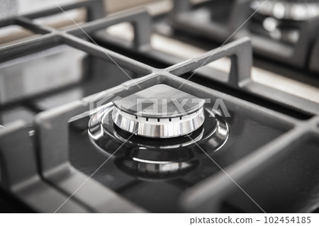 Burner of a new stylish black gas stove close-up with a cast-iron modern grate 102454185