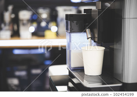 Coffee is poured into a white paper cup from a coffee machine, take away coffee 102454199