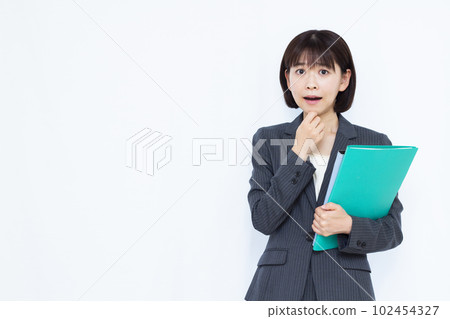 A woman in her thirties in a suit who is surprised in front of a white background 102454327