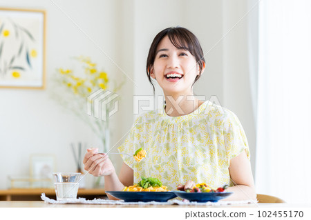 Young woman eating pasta at home 102455170